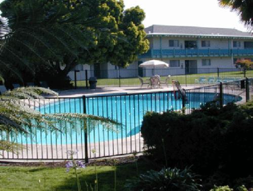 阿拉米达珊瑚公寓套房酒店的一座蓝色的大型游泳池四周设有围栏
