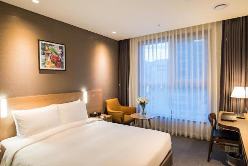 首尔东大门IBC酒店的配有一张床、一张书桌和一扇窗户的酒店客房