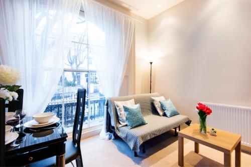 伦敦艾丽西亚南肯辛顿公寓的客厅配有椅子、桌子和窗户