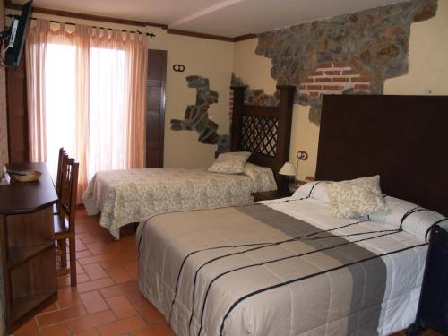 莱德斯马Hotel Rural El Rocal的一间卧室设有两张床和砖墙