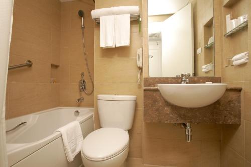 马尼拉St Giles Hotel Makati的浴室配有卫生间、盥洗盆和浴缸。