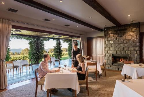 Maryvale趣味尖峰旅舍的坐在带壁炉的餐厅桌子旁的人