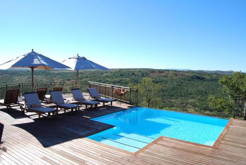 纳姆比提动物保护区Umzolozolo Private Safari Lodge & Spa的甲板上配有椅子和遮阳伞的游泳池