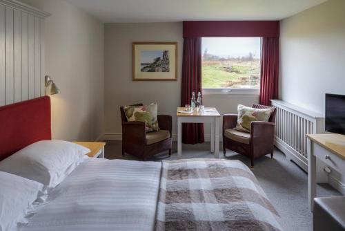 蒂贝Westmorland Hotel Tebay的酒店客房设有床、桌子和窗户。
