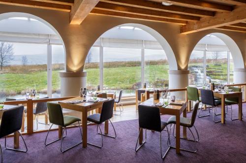 蒂贝Westmorland Hotel Tebay的餐厅设有桌椅和大窗户。