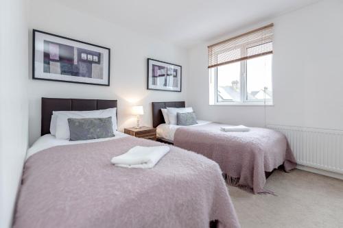 希灵登Royal Apartments - Heathrow的一间卧室设有两张床和窗户。