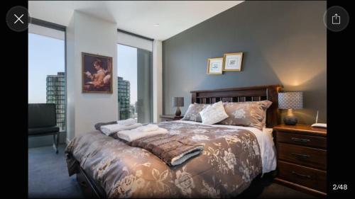 墨尔本梦幻淡水公寓的一间卧室配有一张大床、一张书桌和窗户。