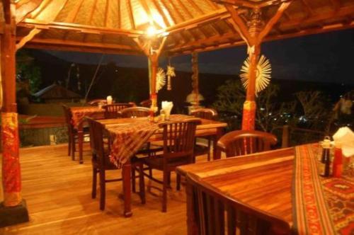 姆杜克阿迪亚芒杜克民宿的一间带木桌和椅子以及遮阳伞的餐厅