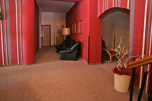Horažďovice兹拉季耶伦酒店的走廊上设有红色的墙壁和黑色的皮沙发