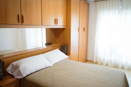 坎布里尔斯Apartamento Port Marino的一间卧室配有一张带木制橱柜的床和窗户。