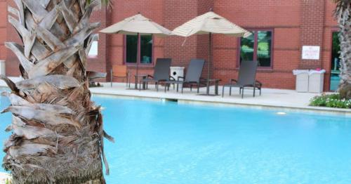 伯锡尔城博姆敦波西尔城酒店的一座带椅子和遮阳伞的游泳池位于一座建筑旁边