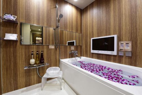 大阪Hotel Bali An Resort Shinsaibashi的浴室设有紫色花瓣覆盖的浴缸。