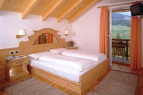 巴迪亚Hotel San Leonardo的一间卧室设有一张大床和一个窗户。