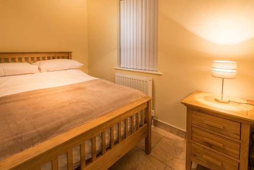 伦敦德里Elagh Cottages的一间卧室配有一张床和一张带台灯的桌子