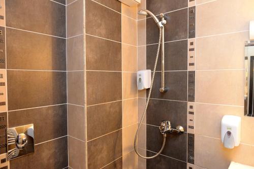 多布里奇Khan Staria Dobrich Family Hotel的一间带淋浴的浴室和瓷砖墙