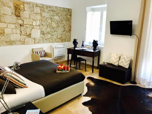 锡拉库扎艾桑提克罗那提酒店的一间卧室配有一张床、一张桌子和一张桌子