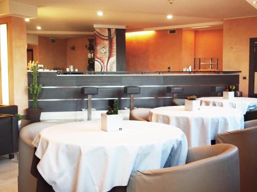 奥佩拉米兰高尔夫酒店的一间设有白色桌椅的餐厅和一间酒吧