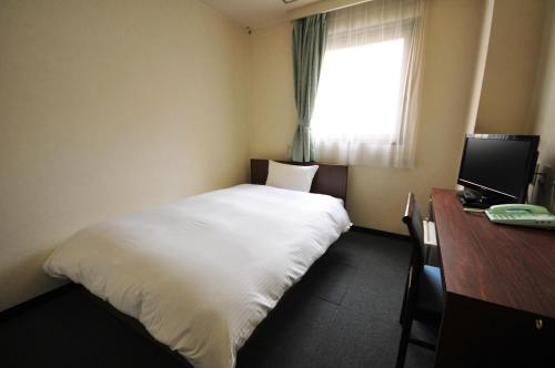 仙台绿城酒店的一间卧室配有一张床、一张书桌和一个窗户。