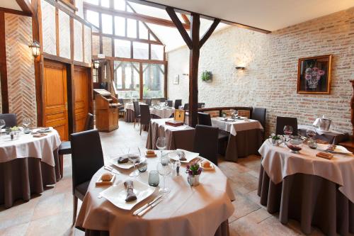 内尔河畔欧比尼La Chaumière的餐厅设有白色的桌椅和窗户。