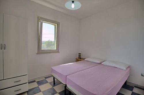 佩斯科勒海滨Mansarda Canarina的卧室配有粉红色的床和窗户。