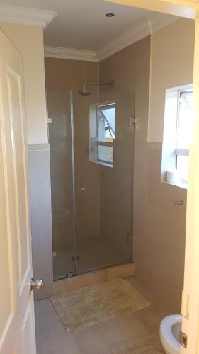 布鲁堡史特兰Natalie Guesthouse的带淋浴的浴室和玻璃门