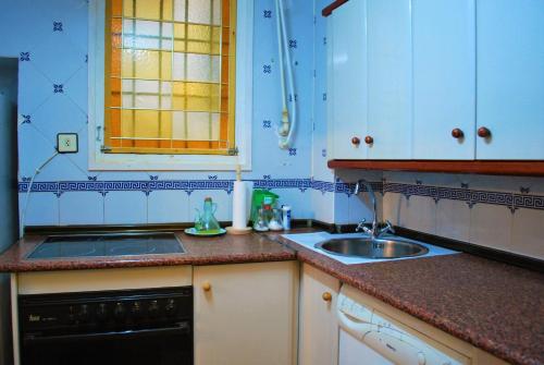 特鲁埃尔Apartamento Tras Catedral的厨房配有水槽、炉灶和窗户。