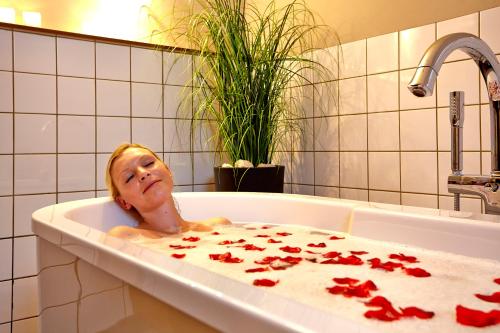 布劳恩拉格relexa hotel Harz-Wald Braunlage GmbH的躺在红色花瓣浴缸中的女人