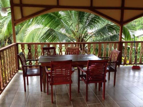 曼萨尼约Suites Chile Verde的棕榈树甲板上的木桌和椅子
