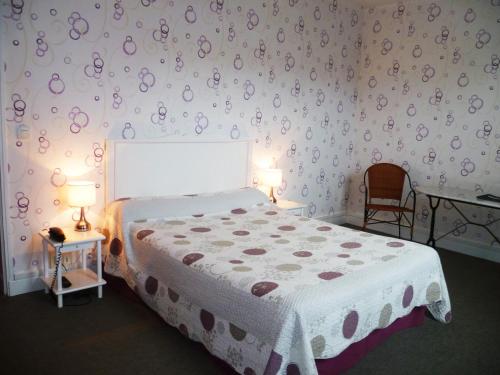 洛特河畔的维伦纽夫拉雷希当斯酒店的一间卧室配有一张床、两张桌子和两盏灯。