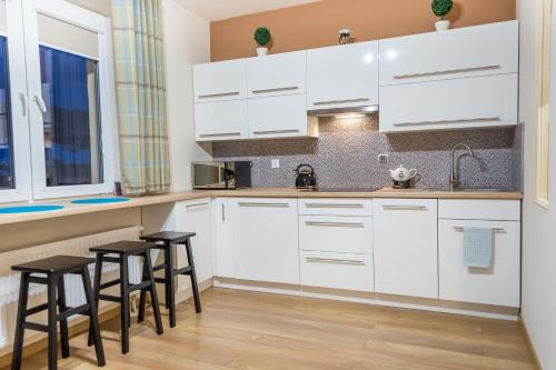 下乌斯奇基Apartament Wygodny的厨房配有白色橱柜和黑色凳子