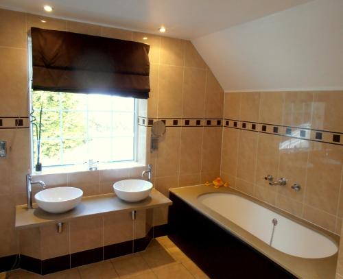 Clutton猎人休息酒店的浴室配有两个盥洗盆和浴缸。