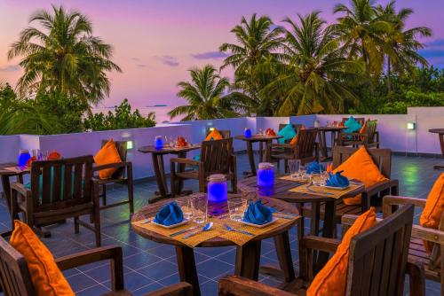 迪古拉海滩潜水全包精品酒店的一间设有桌椅的餐厅,种植了棕榈树