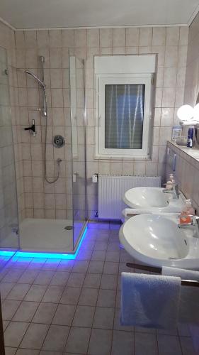 博恩海姆Gästezimmer Junglas的浴室设有2个水槽和带蓝色灯光的淋浴。