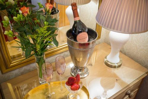 彭里斯Brooklands Guest House的一张桌子,上面放着一瓶葡萄酒、眼镜和鲜花