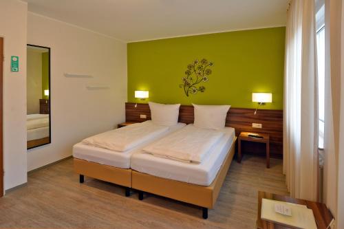 特里尔Hotel L' Angolo的一间卧室设有一张床和绿色的墙壁