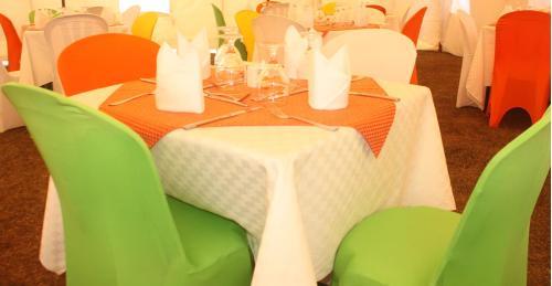 KayonzaSilent Hill Hotel Kayonza的一张桌子、绿色椅子和白色的桌布