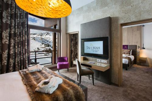 阿克2000Hôtel Taj-I Mah by Les Etincelles的酒店客房设有一张床、一张书桌和一台电视机。