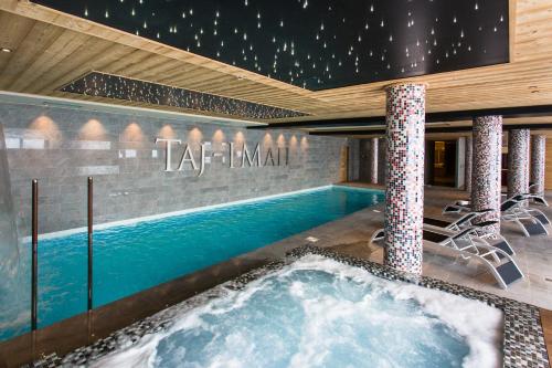 阿克2000Hôtel Taj-I Mah by Les Etincelles的一座大楼内带热水浴池的游泳池