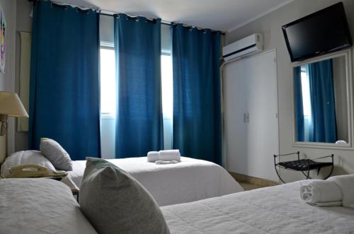 奥拉瓦里亚Hotel Santa Rosa的一间设有两张床和蓝色窗帘的房间