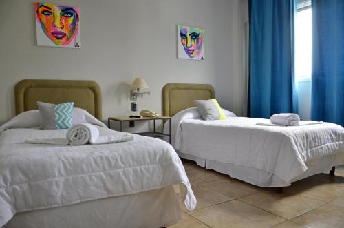 奥拉瓦里亚Hotel Santa Rosa的一间卧室配有两张带白色床单和蓝色窗帘的床