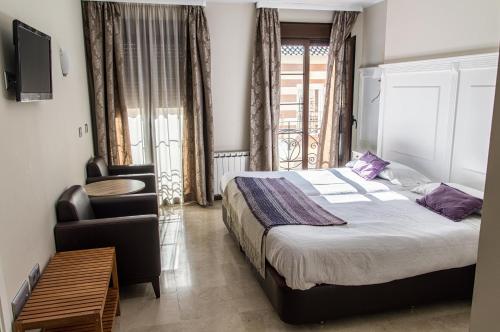 隆达塞维利亚酒店的一间卧室配有一张床、一把椅子和电视