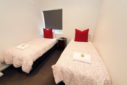 沃加沃加联排别墅公寓的红色枕头间内的两张单人床