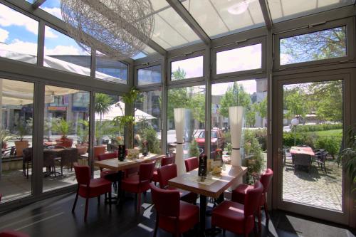 普劳恩City-Hotel的餐厅设有桌椅和大窗户。