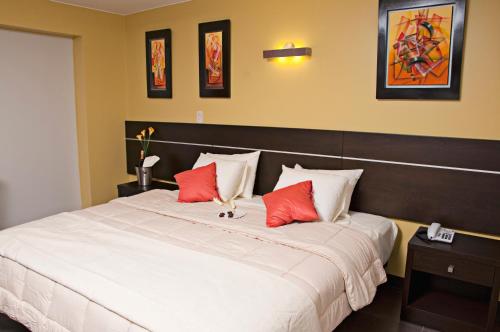利马Flamante Hotel & Suite的卧室配有带红色枕头的大型白色床
