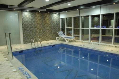 沙迦阿尔哈亚特套房酒店的游泳池位于房子旁,旁边设有椅子