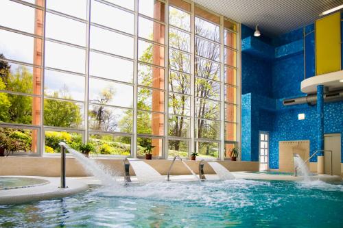 康斯坦丁诺维拉兹内Spa Hotel Garni Löwenstein的一座带窗户的建筑中一个带喷水装置的游泳池