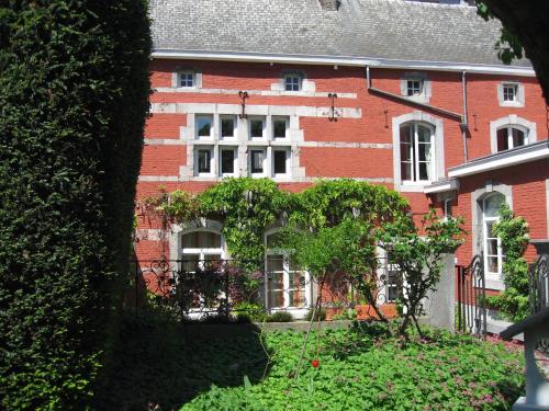 于伊Chambre d'Hôtes Les Augustins - Parking sécurisé - Borne de recharge的一座红砖建筑,前面有一个花园