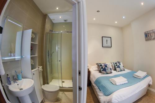 亨顿Finchley Central Spacious 3 bed triplex loft style apartment的配有床、淋浴和盥洗盆的浴室