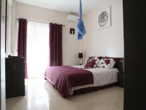 达喀尔Apartment 25B11 Mixta的一间卧室配有一张带紫色床单的床和窗户。