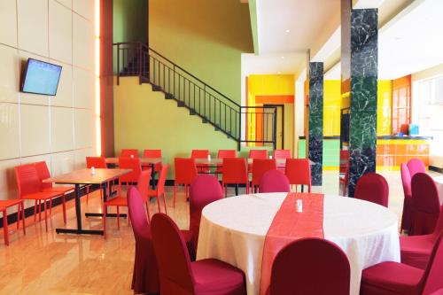 美娜多美娜多马洛桑酒店的用餐室配有桌子和红色椅子
